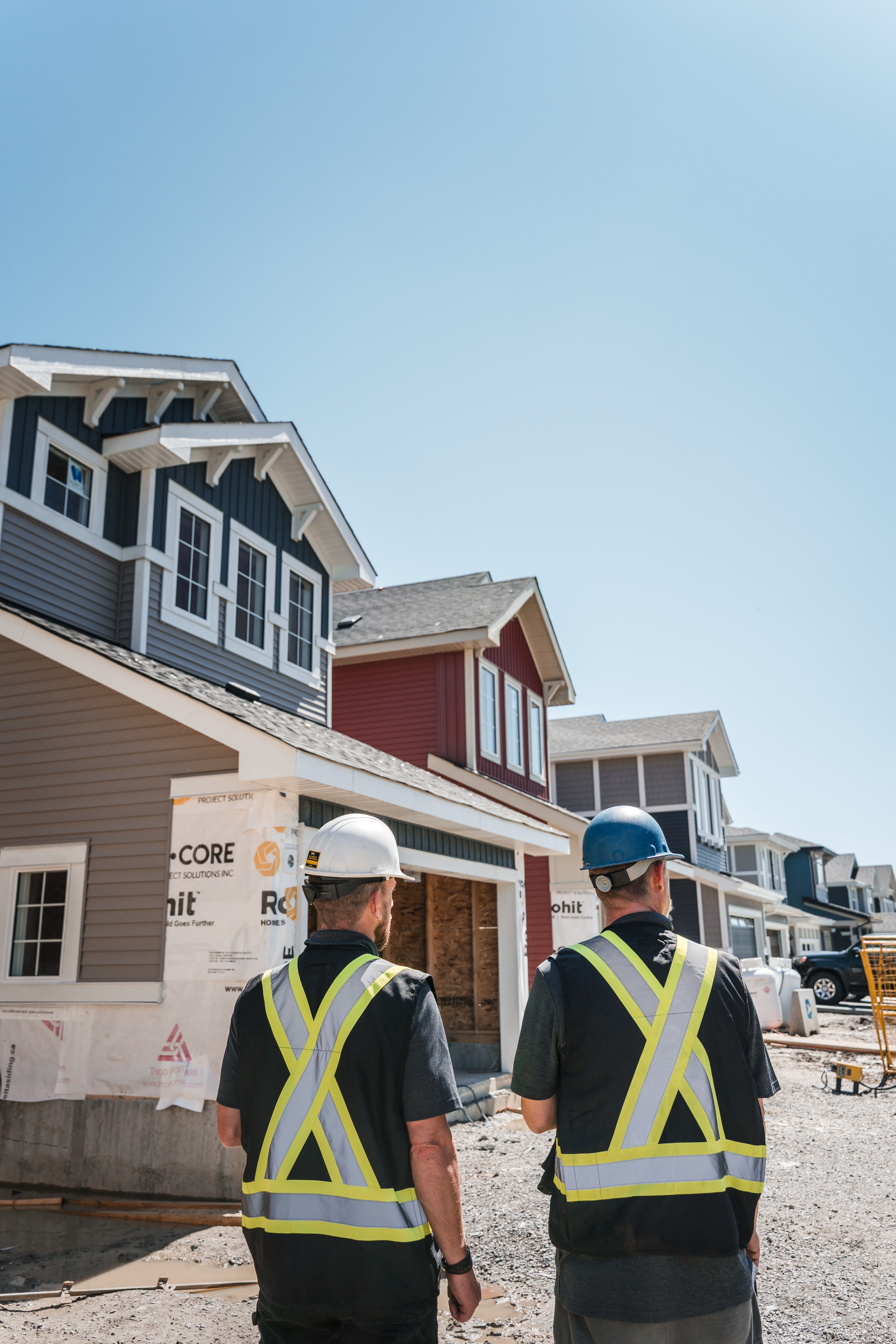 Construction management software for home builders: two builders in hard hats looking at homes under construction